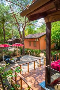 a wooden deck with red umbrellas and a house at Camping Lacona Pineta in Capoliveri