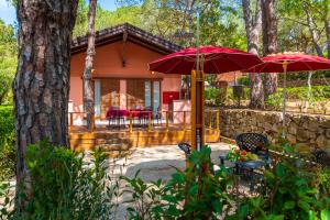 une maison avec 2 parasols rouges et une terrasse dans l'établissement Camping Lacona Pineta, à Capoliveri