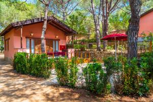 a house in the woods with an umbrella at Camping Lacona Pineta in Capoliveri