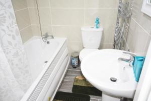 a bathroom with a toilet and a sink and a tub at London Zone 2 Three Bedroom Apartment in London