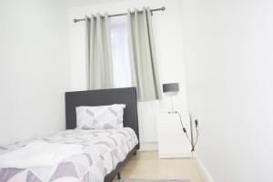 a white bedroom with a bed and a window at London Zone 2 Three Bedroom Apartment in London