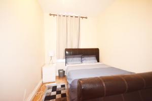 a bedroom with a bed and a leather couch at London Zone 2 Three Bedroom Apartment in London