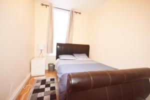 a bedroom with a bed with a brown leather couch at London Zone 2 Three Bedroom Apartment in London