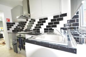 a kitchen with a sink and black and white tiles at London Zone 2 Three Bedroom Apartment in London