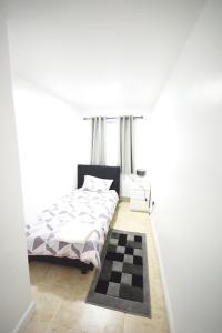 a bedroom with a bed and a checkered rug at London Zone 2 Three Bedroom Apartment in London