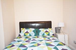 a bedroom with a bed with a colorful comforter at London Zone 2 Three Bedroom Apartment in London