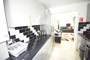 a kitchen with a sink and a living room at London Zone 2 Three Bedroom Apartment in London