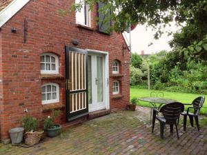 a brick house with a table and chairs in front of it at Jabjemööh's Huus in Greetsiel