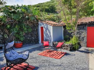 two chairs sitting in a yard with a building at Casinha de Nesquim in Calheta de Nesquim