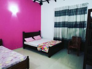 ネゴンボにあるAhasna Family Villaのピンクの壁のベッドルーム1室(ベッド2台付)