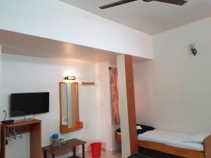 a room with two beds and a flat screen tv at Sri Kumara Lodge in Bangalore
