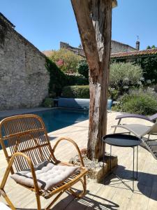 a chair and table next to a tree next to a pool at La Petite Maison in Laroque-Timbaut