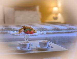 une table avec une assiette de nourriture et deux tasses de café dans l'établissement Hotel Aurora, à Vallarsa