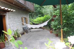 a hammock on a patio with a house at Cantinho do Bouço Velho in Couto de Baixo