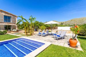 einen Pool in einem Garten mit Stühlen und einem Sonnenschirm in der Unterkunft Villa Melis Dos in Pollença