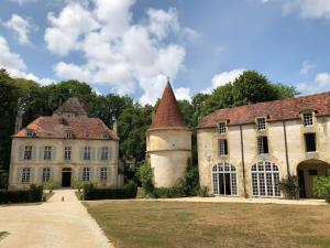 ein altes Gebäude mit einem Turm auf einem Feld in der Unterkunft Orangerie du chateau de Quemigny sur Seine in Quemigny-sur-Seine