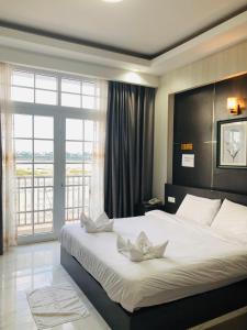 a bedroom with a large white bed with a large window at Sunset Mekong Apartment in Vientiane