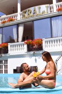 a man and woman sitting in a swimming pool at Hotel Kralj in Vrnjačka Banja
