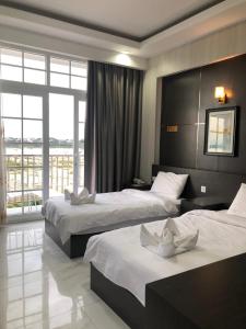 a hotel room with two beds and a large window at Sunset Mekong Apartment in Vientiane +20 photos