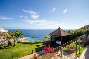 een tuin met een tuinhuisje en de oceaan bij Serenity Amadores in Puerto Rico de Gran Canaria