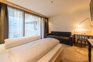 a bedroom with a bed and a couch and a window at Hotel Alpenrast in Riva di Tures