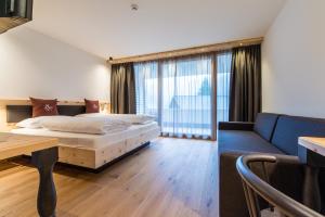 リヴァ・ディ・トゥーレスにあるHotel Alpenrastのベッドルーム1室(ベッド1台、ソファ、テーブル付)