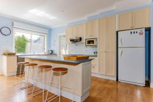 a kitchen with a white refrigerator and bar with stools at WALKIN ON SUNSHINE - STROLL TO BEACH BREAK in Inverloch