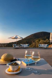 einen Tisch mit zwei Gläsern Wein und eine Schüssel Essen in der Unterkunft Borgo d'Orlando - Country Boutique Hotel in Mirto