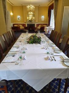 スウィンドンにあるChiseldon House Hotelの白いテーブルクロス付きの長テーブル