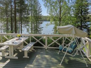 a picnic table and a chair on a deck with a lake at Holiday Home Sipukka by Interhome in Meltaus