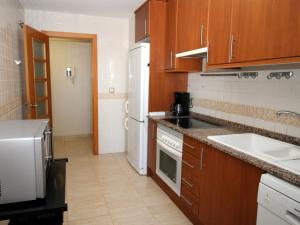 a kitchen with wooden cabinets and a white refrigerator at Apartment Torre Maestral-1 by Interhome in Cala de Finestrat
