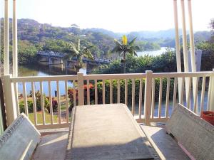 a table and chairs on a balcony with a view of a river at The Tweni Waterfront Guest Lodge in Port Shepstone