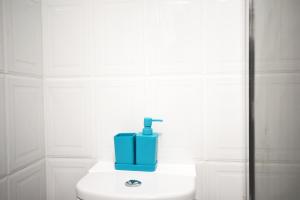 een blauwe zeepdispenser op een toilet in een badkamer bij London Modern One Bedroom Apartment in Londen
