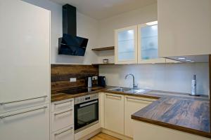 a kitchen with white cabinets and a sink and a stove at English Theater Apartment at Rathaus in Vienna