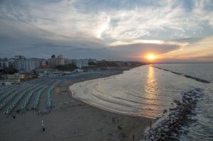 a beach with umbrellas and the ocean with the sunset at Residenza Giannini in Termoli