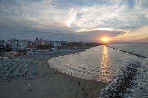 a beach with umbrellas and the ocean with the sunset at Residenza Giannini a Termoli in Termoli