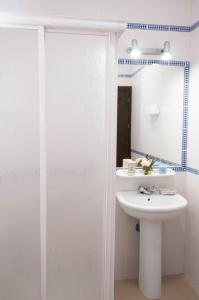 Baño blanco con lavabo y espejo en Apartamentos Conil Alquila, en Conil de la Frontera