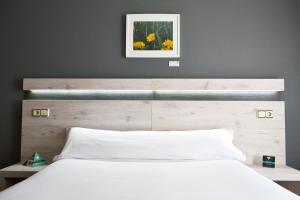 a bedroom with a white bed with a wooden headboard at Alda Puerta Coruña in A Coruña