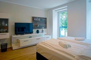 a white bedroom with two beds and a flat screen tv at English Theater Apartment at Rathaus in Vienna