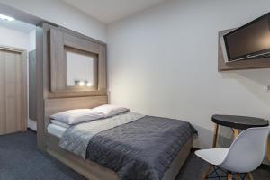 a bedroom with a bed and a table and a television at Willa Lala in Szczawnica