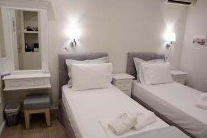two beds in a small room with a mirror at LEVANTA HOTEL SPETSES in Spetses