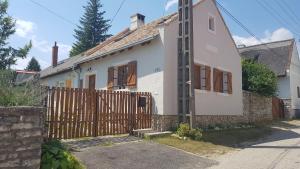 ein weißes Haus mit einem Holztor und einem Zaun in der Unterkunft Koloska House in Balatonfüred