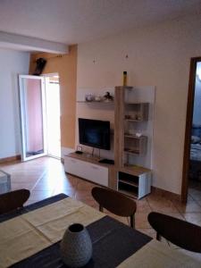 a living room with a television and a table and chairs at Apartment Kisic in Fažana