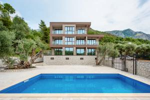 a house with a swimming pool in front of a building at Adria lux apartmens 2 in Sveti Stefan