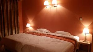 a bedroom with a large bed with two lights on the wall at Otroiza Hotel in Cilaos