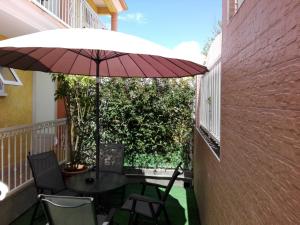 un patio con mesa, sillas y sombrilla en Otroiza Hotel, en Cilaos
