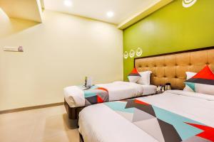 um quarto com 2 camas e uma parede verde em FabHotel Landmark Guestline Vashi em Navi Mumbai