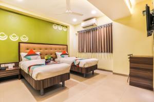 two beds in a room with green walls at FabHotel Landmark Guestline Vashi in Navi Mumbai