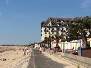 a building on the beach with people on the beach at Studio Les Pieds dans l'eau in Donville-les-Bains