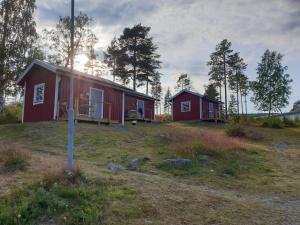 um par de cabanas vermelhas num campo com árvores em Måvikens Camping em Måviken